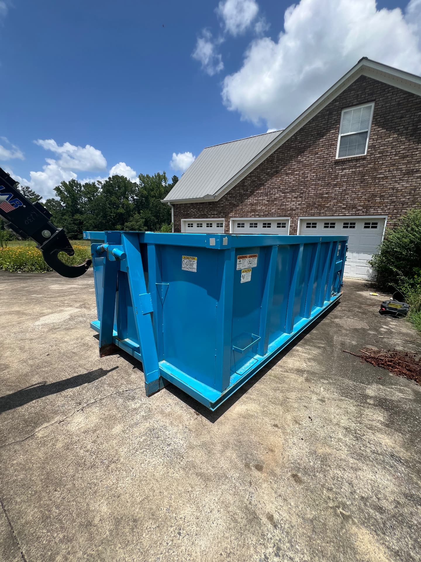 Blue roll off dumpster set on a residential driveway in Calhoun County, Alabama