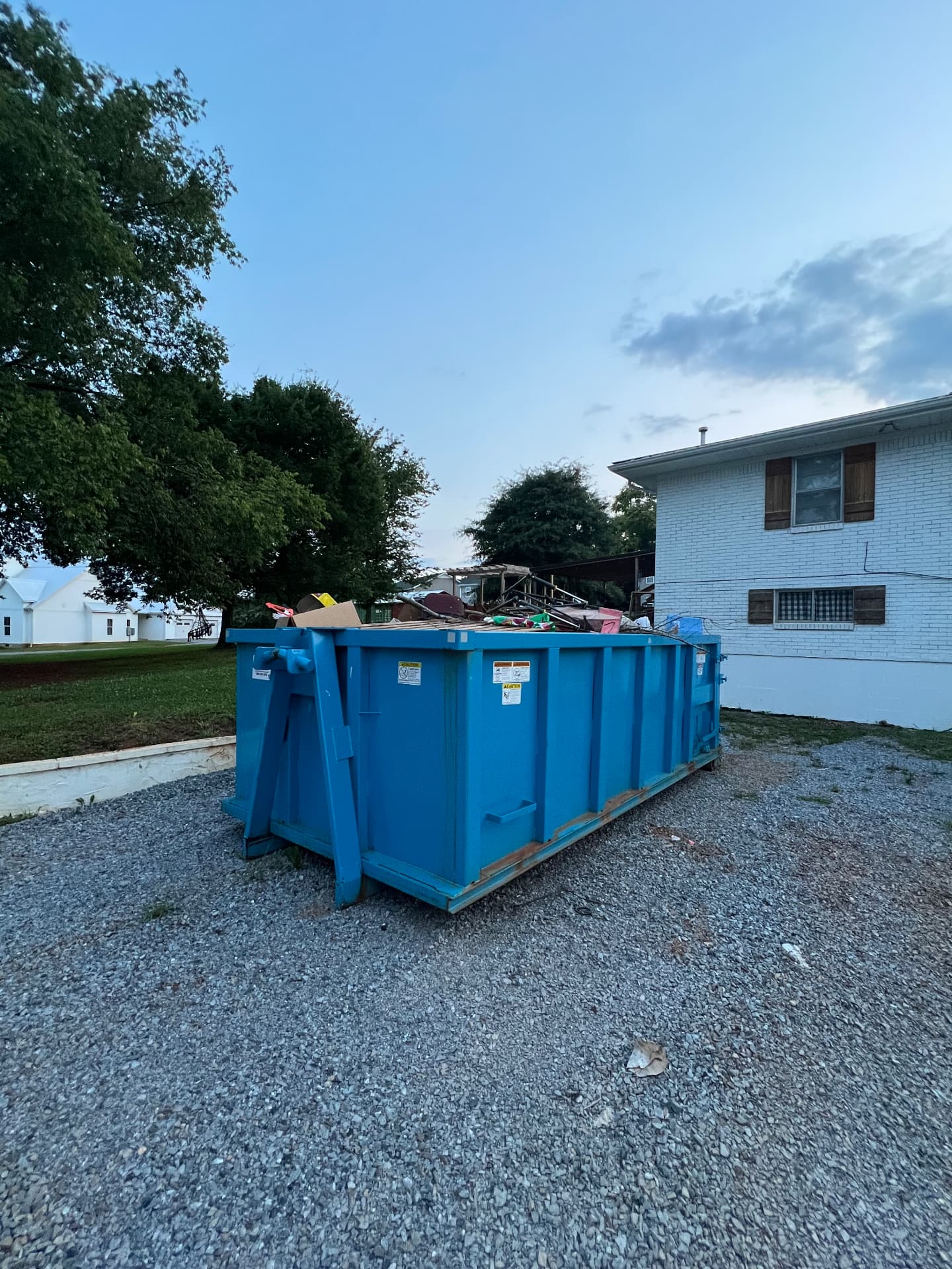 Blue 20 yard roll off dumpster filled with construction debris on a gravel pad