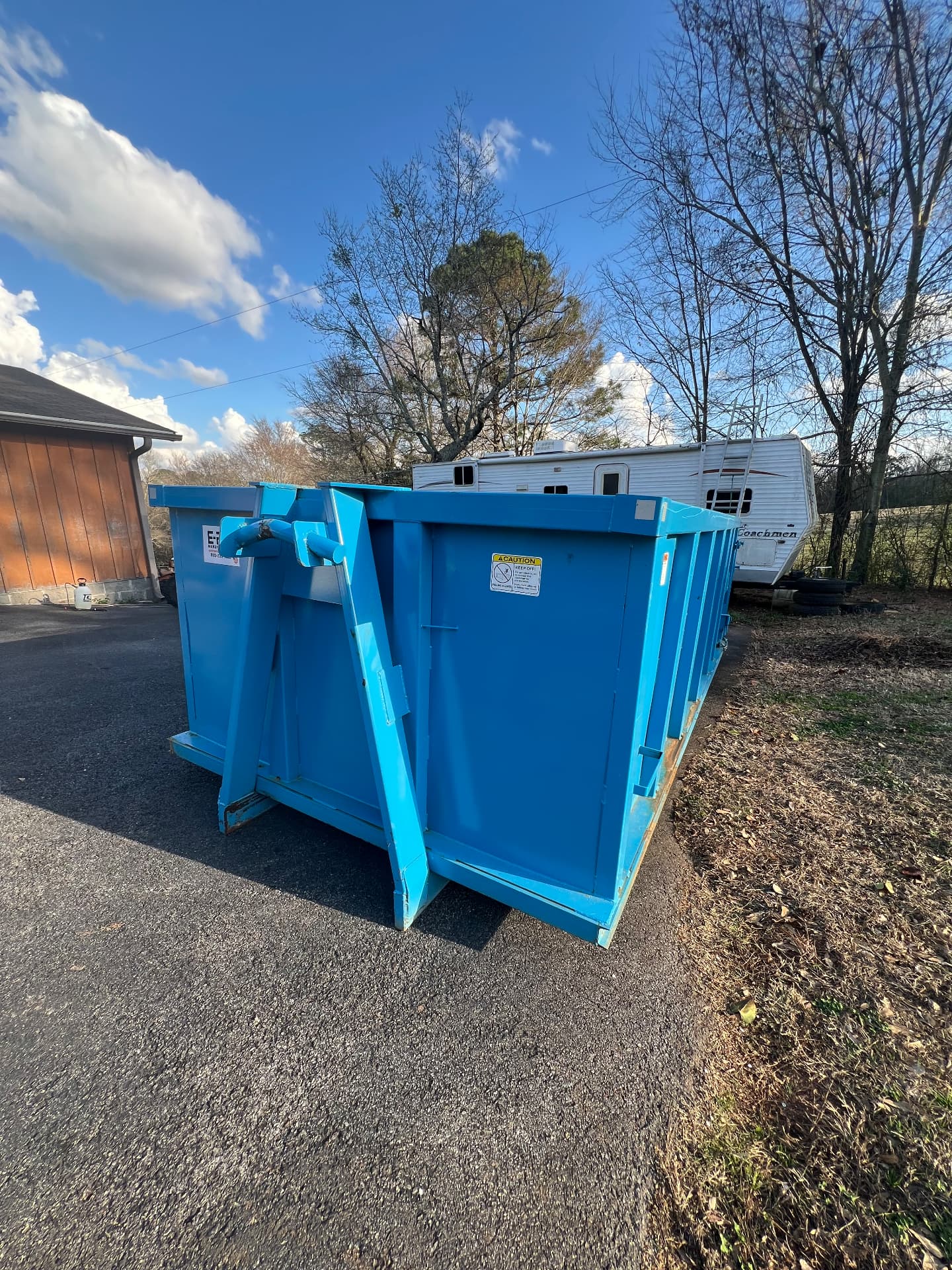 Clean blue roll off dumpster with swing door parked on a driveway